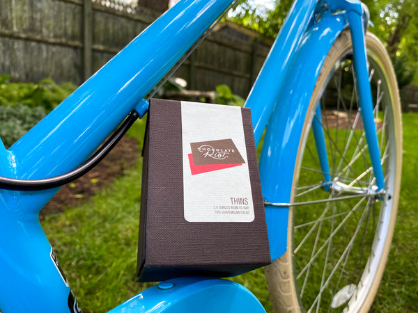 a small brown box with a white label sitting atop a bright blue bicycle