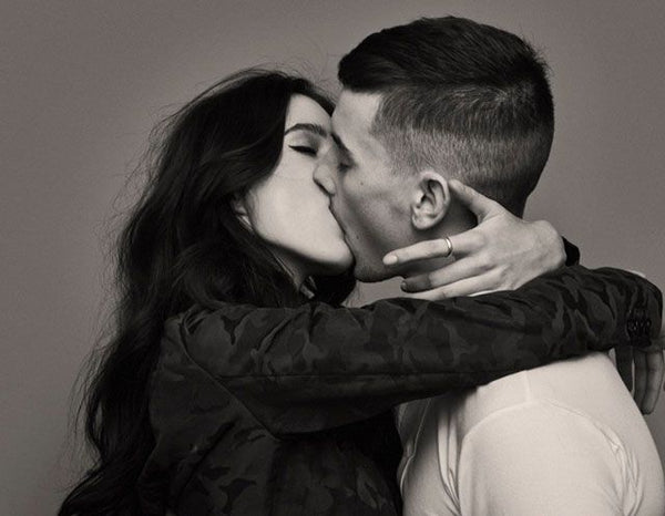 a black and white photo of a man and a woman kissing passionately and embracing