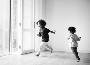 a black and white image of young children happily running inside a house