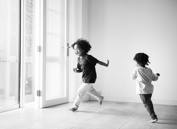 a black and white image of young children happily running inside a house