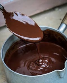 melted liquid chocolate in a pan with some dribbling from a spoon