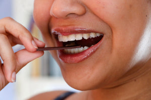 a smiling woman placing a Tangle Chocolate thin on her tongue