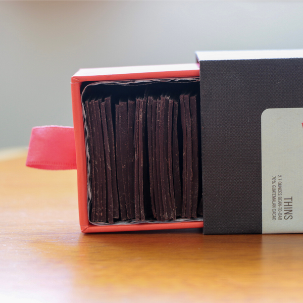 an open box of Tangle Chocolate dark chocolate thins, lying on its side on a wooden table