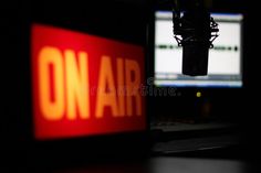 a bright red and yellow sign that reads 'ON AIR', with a microphone hanging from above in the background