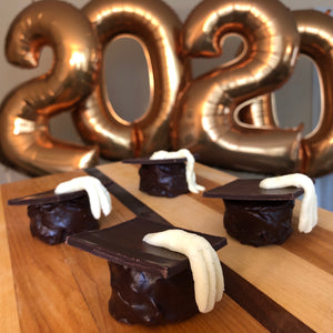 chocolate graduation caps with white chocolate tassels with giant gold balloons in the shape of "2020"